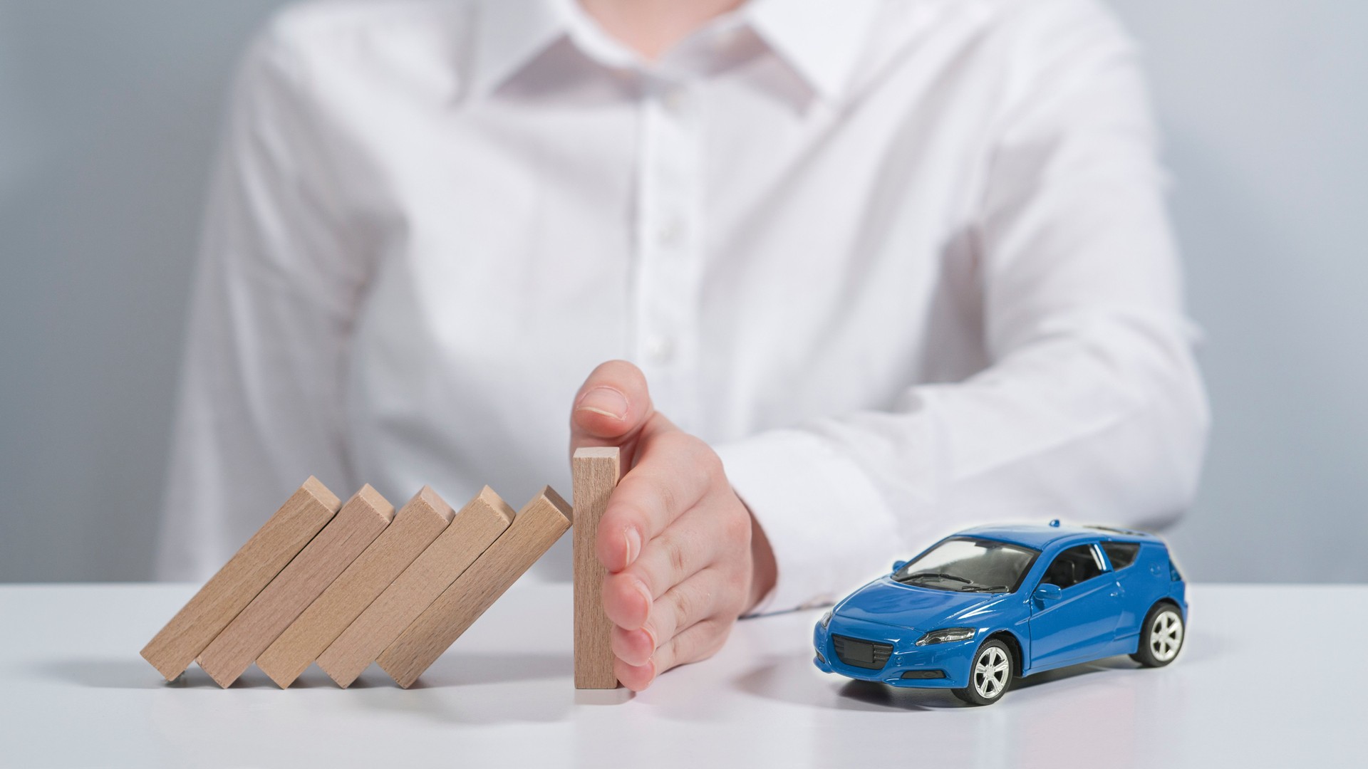 Next to the little blue car is a person's hand that prevents dangers from coming to her.